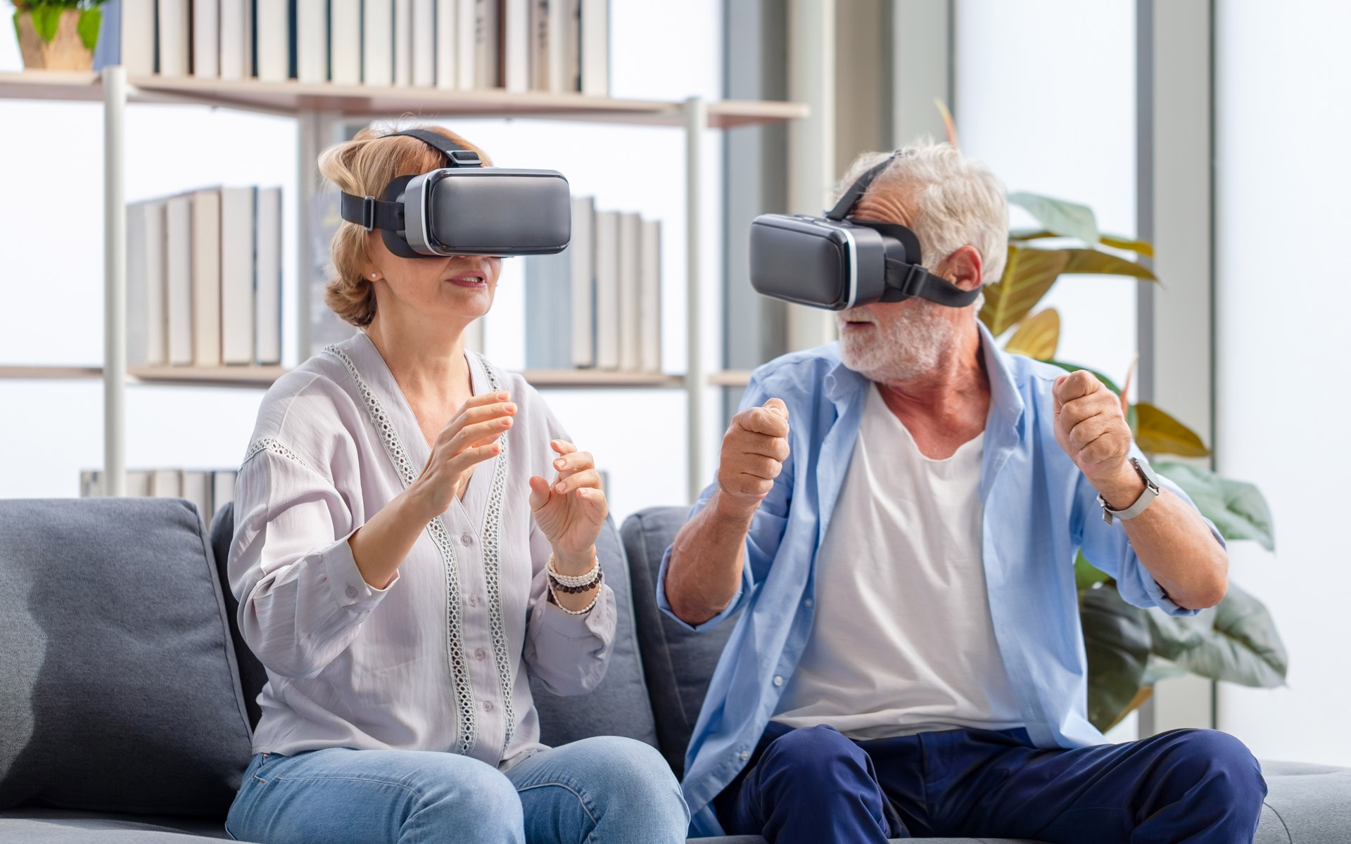 An older couple using virtual reality headsets at home